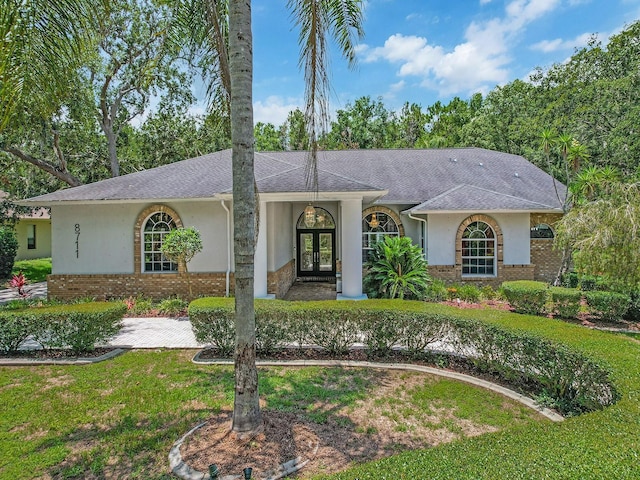 8711 Crescent Forest Blvd, New Port Richey, FL 34654 - ranch-style house featuring french doors, stucco siding, brick siding, and a front yard