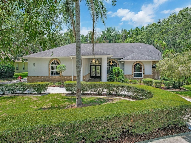 8711 Crescent Forest Blvd, New Port Richey, FL 34654 - ranch-style house with french doors, brick siding, stucco siding, and a front yard