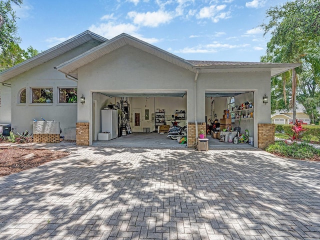 8711 Crescent Forest Blvd, New Port Richey, FL 34654 - garage featuring decorative driveway and freestanding refrigerator