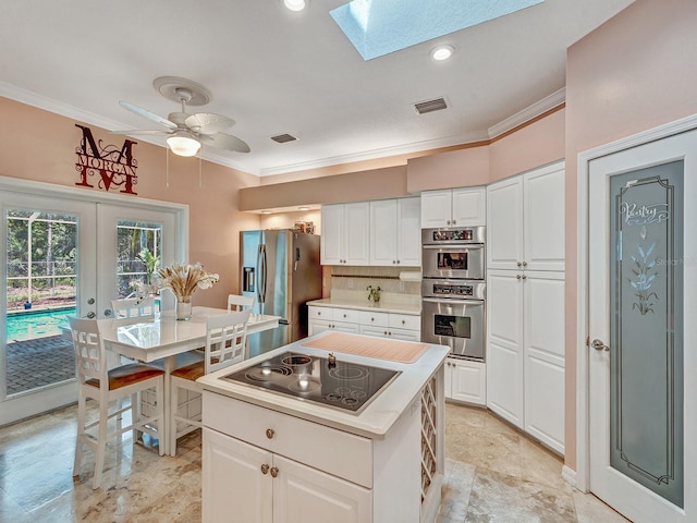 8711 Crescent Forest Blvd, New Port Richey, FL 34654 - kitchen with appliances with stainless steel finishes, crown molding, a skylight, white cabinetry, and light countertops