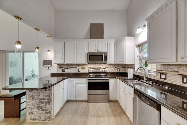 9041 58th St N, Pinellas Park, FL 33782 - kitchen featuring stainless steel appliances, a peninsula, light wood finished floors, white cabinets, and a towering ceiling
