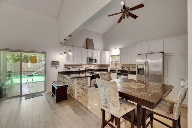 9041 58th St N, Pinellas Park, FL 33782 - kitchen featuring stainless steel appliances, high vaulted ceiling, dark countertops, a peninsula, and light wood-type flooring