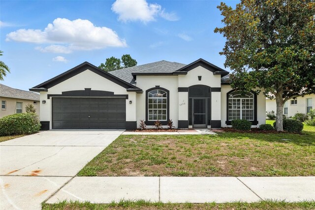 5390 Greystone Dr, Spring Hill, FL 34609 - view of front of house featuring stucco siding, a front yard, an attached garage, driveway, and roof with shingles