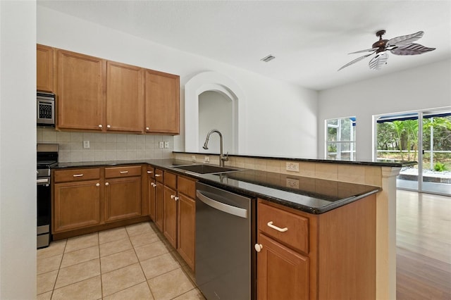 5390 Greystone Dr, Spring Hill, FL 34609 - kitchen featuring appliances with stainless steel finishes, a peninsula, tasteful backsplash, and brown cabinetry
