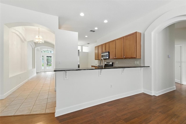 5390 Greystone Dr, Spring Hill, FL 34609 - kitchen featuring stainless steel microwave, dark countertops, a peninsula, brown cabinets, and recessed lighting