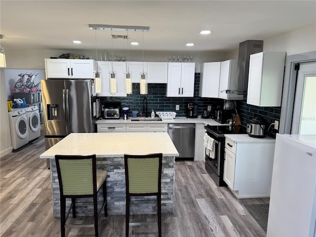 2509 Thornbrook Pl, Tampa, FL 33618 - kitchen featuring washing machine and dryer, stainless steel appliances, wall chimney range hood, light countertops, and wood finished floors