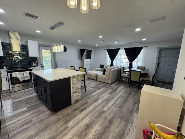 2509 Thornbrook Pl, Tampa, FL 33618 - kitchen featuring wall chimney exhaust hood, stainless steel range with electric stovetop, light countertops, dark cabinetry, and wood finished floors