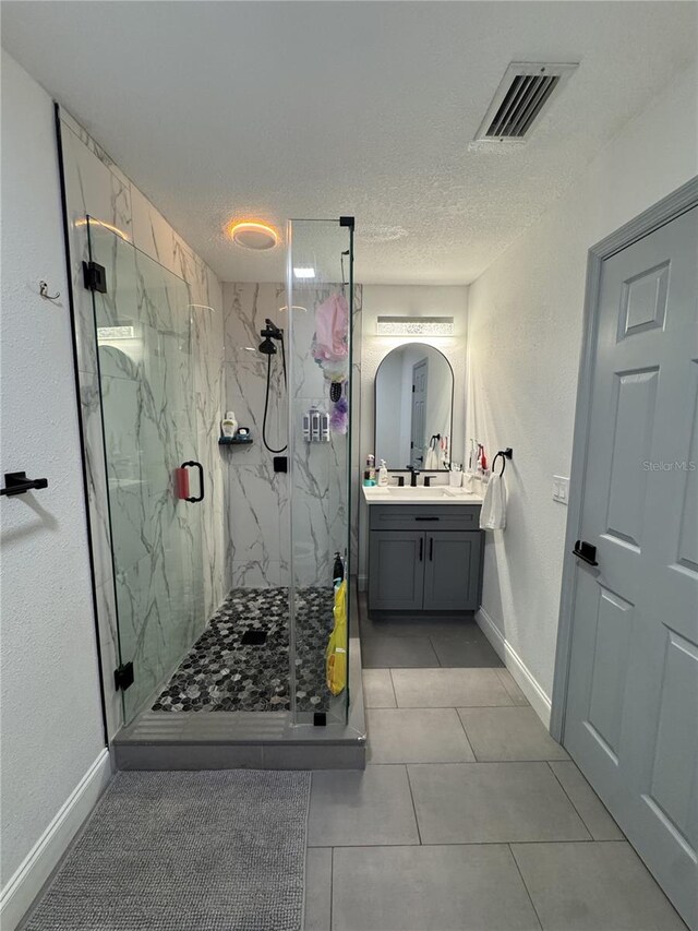 2509 Thornbrook Pl, Tampa, FL 33618 - bathroom featuring vanity, a marble finish shower, a textured ceiling, and tile patterned flooring