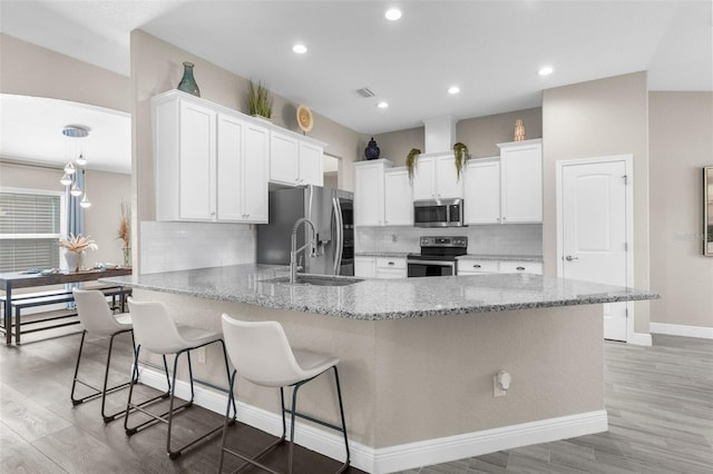 12333 Harris Hawk Rd, Weeki Wachee, FL 34614 - kitchen with appliances with stainless steel finishes, a peninsula, light stone countertops, light wood-style flooring, and recessed lighting