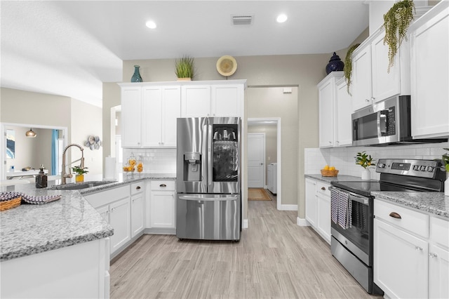 12333 Harris Hawk Rd, Weeki Wachee, FL 34614 - kitchen with appliances with stainless steel finishes, white cabinets, tasteful backsplash, light wood finished floors, and recessed lighting