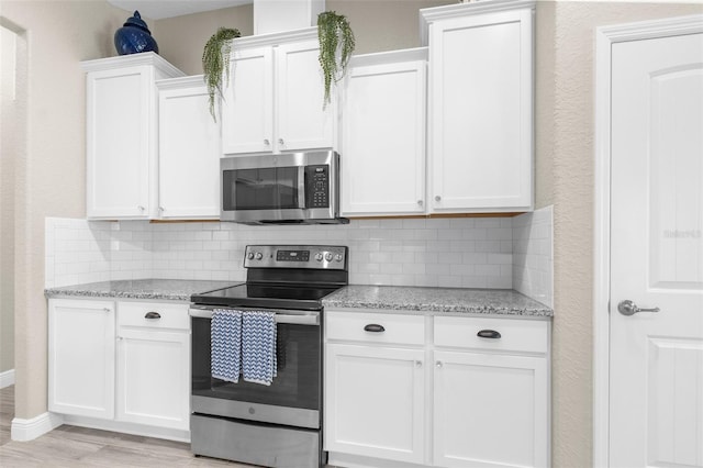 12333 Harris Hawk Rd, Weeki Wachee, FL 34614 - kitchen featuring appliances with stainless steel finishes, tasteful backsplash, and white cabinetry