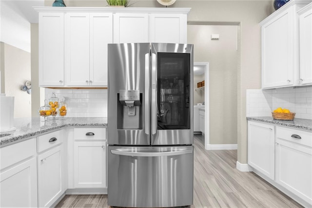 12333 Harris Hawk Rd, Weeki Wachee, FL 34614 - kitchen with stainless steel refrigerator with ice dispenser, decorative backsplash, light wood finished floors, white cabinets, and light stone counters