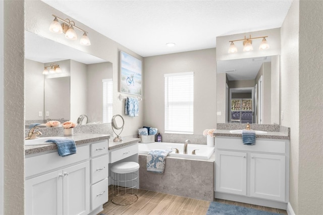 12333 Harris Hawk Rd, Weeki Wachee, FL 34614 - full bathroom with two vanities, a garden tub, a textured wall, and wood tiled floors