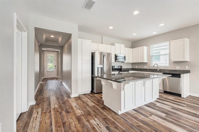 12322 Eagle Swoop Pl, Riverview, FL 33579 - kitchen featuring appliances with stainless steel finishes, a kitchen bar, dark wood-type flooring, white cabinets, and a kitchen island