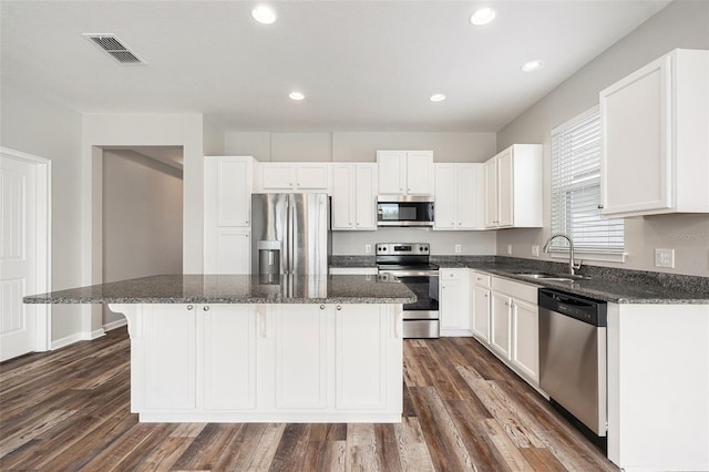 12322 Eagle Swoop Pl, Riverview, FL 33579 - kitchen with appliances with stainless steel finishes, a kitchen island, white cabinets, recessed lighting, and dark wood finished floors