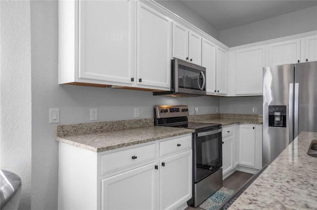 3921 SW 51st Ter, Ocala, FL 34474 - kitchen featuring appliances with stainless steel finishes, white cabinetry, dark wood-style floors, and light stone counters