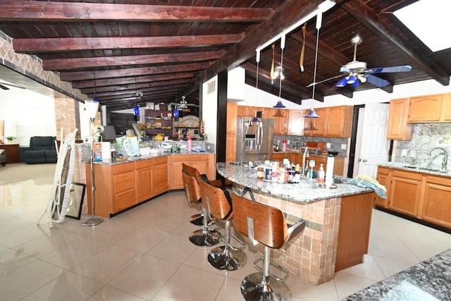 21921 US Highway 98, Dade City, FL 33523 - kitchen with stainless steel fridge, tasteful backsplash, light stone countertops, light tile patterned flooring, and an island with sink