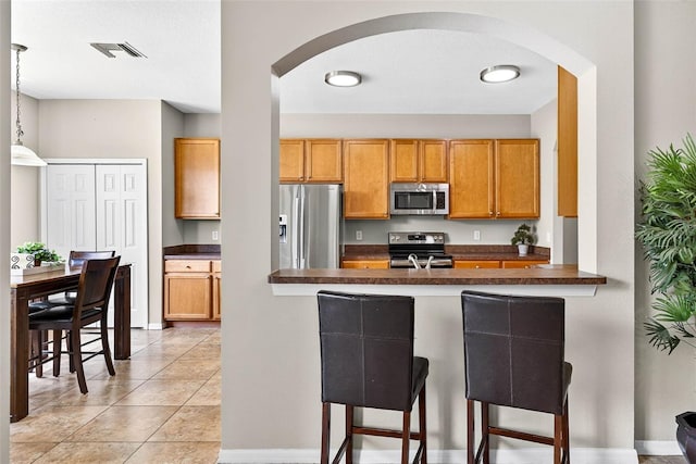 19028 Narimore Dr, Land O Lakes, FL 34638 - kitchen featuring stainless steel appliances, arched walkways, dark countertops, and a breakfast bar