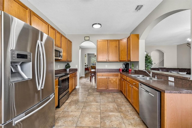 19028 Narimore Dr, Land O Lakes, FL 34638 - kitchen with appliances with stainless steel finishes, dark countertops, a peninsula, and arched walkways