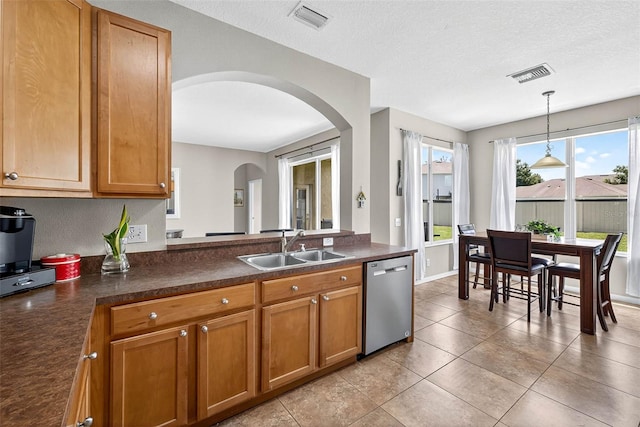 19028 Narimore Dr, Land O Lakes, FL 34638 - kitchen featuring stainless steel dishwasher, arched walkways, dark countertops, brown cabinets, and hanging light fixtures