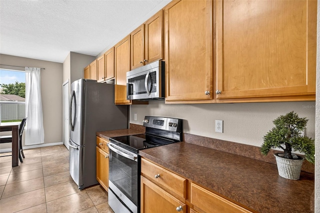 19028 Narimore Dr, Land O Lakes, FL 34638 - kitchen featuring stainless steel appliances, dark countertops, light tile patterned flooring, and a textured ceiling