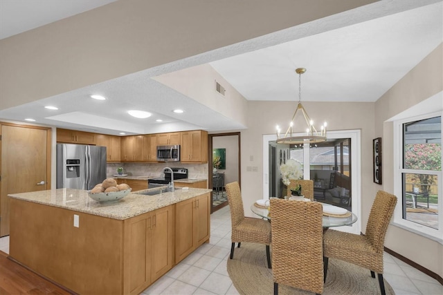 2174 Kent Ave, Clearwater, FL 33764 - kitchen with appliances with stainless steel finishes, a chandelier, light stone counters, tasteful backsplash, and a center island with sink