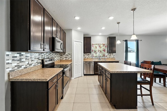 303 Briarbrook Ln, Haines City, FL 33844 - kitchen featuring appliances with stainless steel finishes, a kitchen island, a kitchen breakfast bar, backsplash, and light countertops