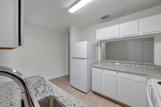 1302 Twilridge Pl, Brandon, FL 33511 - kitchen featuring white appliances, white cabinetry, light tile patterned floors, a textured ceiling, and light stone counters