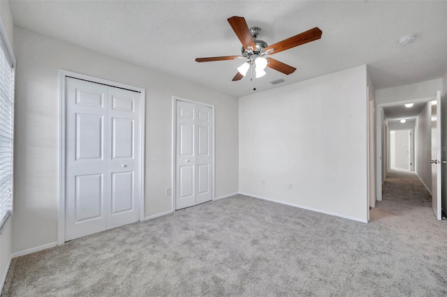 1302 Twilridge Pl, Brandon, FL 33511 - unfurnished bedroom featuring multiple closets, carpet floors, a textured ceiling, and a ceiling fan