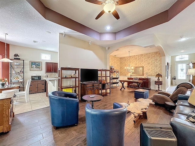 12200 Hunters Lake Dr, New Port Richey, FL 34654 - living room with arched walkways, ceiling fan, a chandelier, a textured ceiling, and wood finished floors