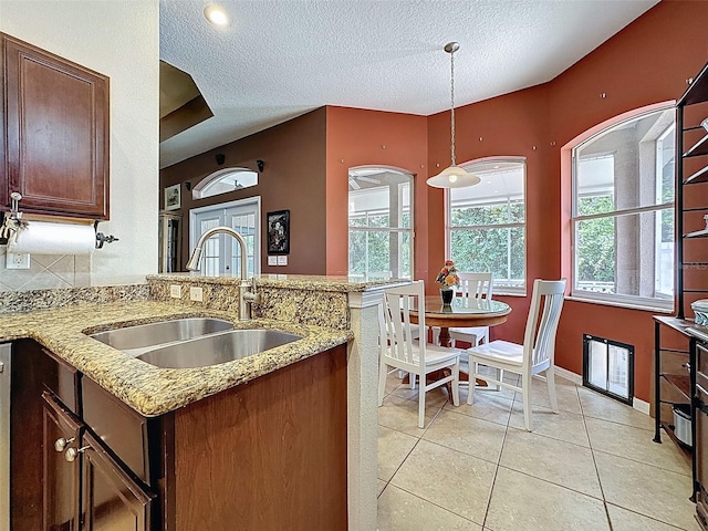 12200 Hunters Lake Dr, New Port Richey, FL 34654 - kitchen with a textured ceiling, light tile patterned floors, hanging light fixtures, light stone counters, and a peninsula