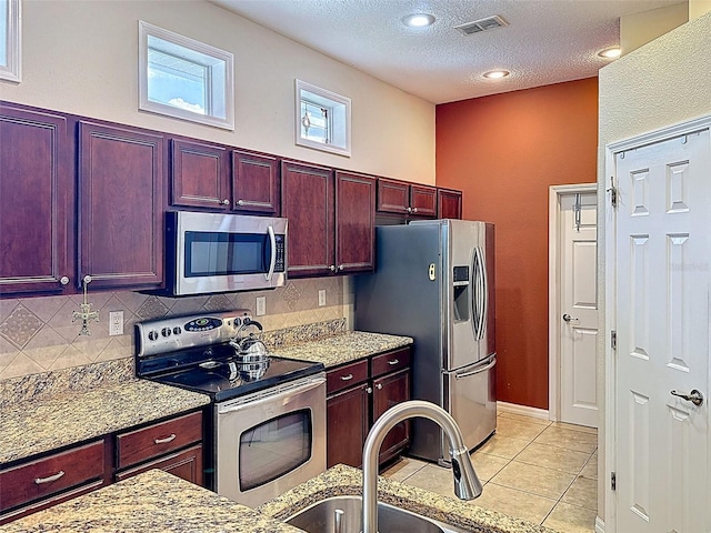 12200 Hunters Lake Dr, New Port Richey, FL 34654 - kitchen with stainless steel appliances, reddish brown cabinets, backsplash, light tile patterned floors, and light stone counters