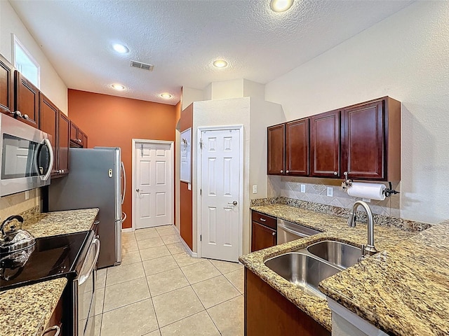 12200 Hunters Lake Dr, New Port Richey, FL 34654 - kitchen with stainless steel appliances, stone countertops, a textured ceiling, light tile patterned flooring, and reddish brown cabinets