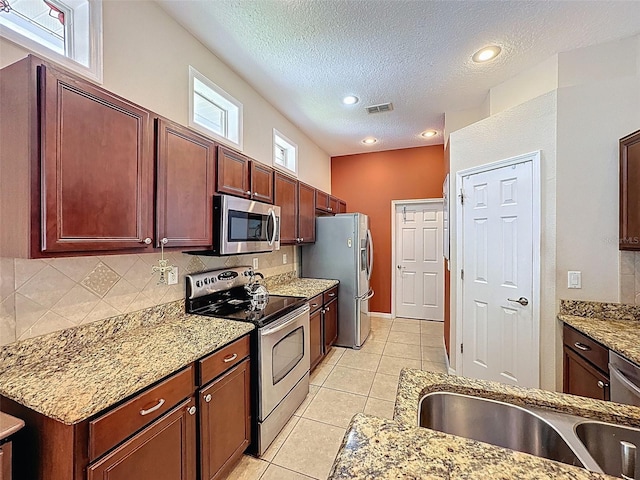 12200 Hunters Lake Dr, New Port Richey, FL 34654 - kitchen with appliances with stainless steel finishes, backsplash, a textured ceiling, light stone counters, and light tile patterned flooring