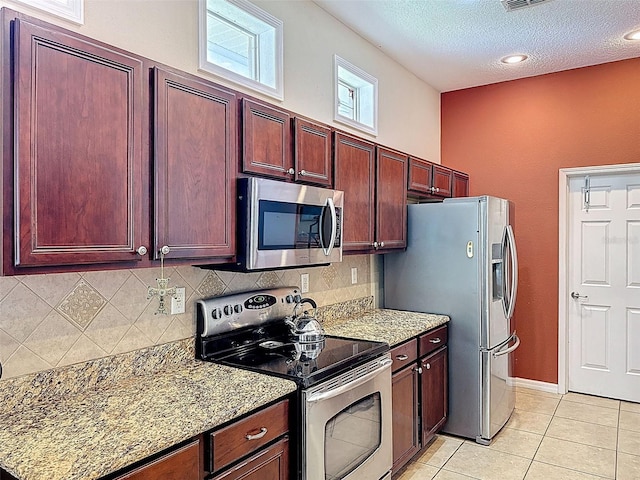 12200 Hunters Lake Dr, New Port Richey, FL 34654 - kitchen with appliances with stainless steel finishes, dark brown cabinets, decorative backsplash, light tile patterned floors, and light stone counters