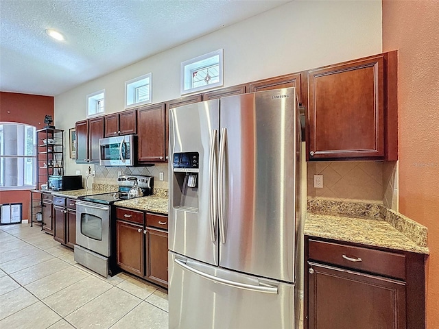 12200 Hunters Lake Dr, New Port Richey, FL 34654 - kitchen featuring appliances with stainless steel finishes, tasteful backsplash, light tile patterned floors, a textured ceiling, and light stone counters