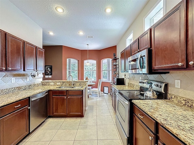 12200 Hunters Lake Dr, New Port Richey, FL 34654 - kitchen with appliances with stainless steel finishes, a peninsula, a textured ceiling, decorative backsplash, and light stone countertops