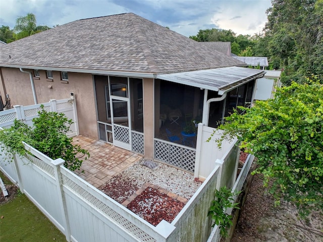 12200 Hunters Lake Dr, New Port Richey, FL 34654 - view of side of property featuring roof with shingles, a fenced backyard, a sunroom, and stucco siding