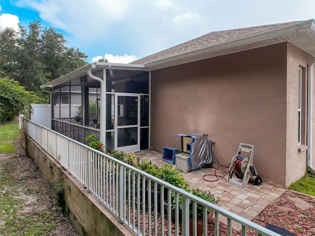 12200 Hunters Lake Dr, New Port Richey, FL 34654 - view of side of home featuring a sunroom, a patio, and stucco siding