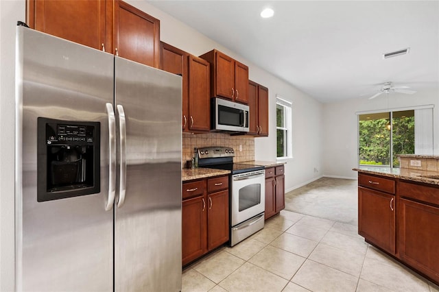 11144 Paradise Point Way, New Port Richey, FL 34654 - kitchen with appliances with stainless steel finishes, tasteful backsplash, light colored carpet, light stone counters, and a ceiling fan