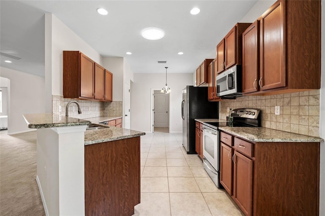 11144 Paradise Point Way, New Port Richey, FL 34654 - kitchen featuring stainless steel appliances, a peninsula, backsplash, light stone countertops, and decorative light fixtures