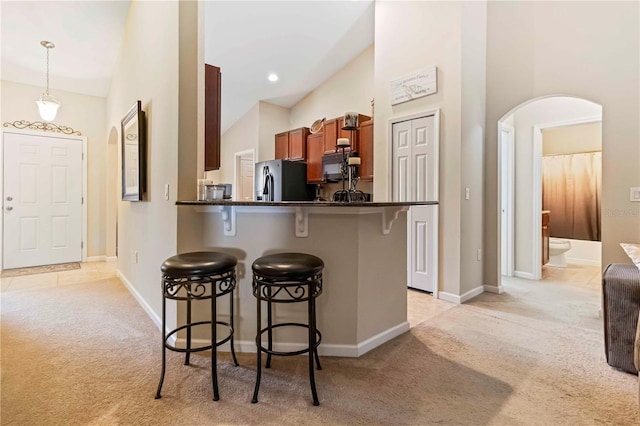 5264 Brilliance Cir, Cocoa, FL 32926 - kitchen with light carpet, arched walkways, a breakfast bar area, and refrigerator with ice dispenser