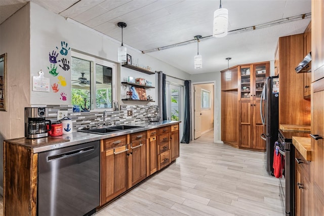 1403 Tallahassee Dr, Tarpon Springs, FL 34689 - kitchen with appliances with stainless steel finishes, brown cabinetry, backsplash, light wood-style floors, and pendant lighting