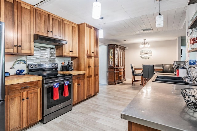 1403 Tallahassee Dr, Tarpon Springs, FL 34689 - kitchen featuring stainless steel appliances, under cabinet range hood, light wood-style flooring, and brown cabinets