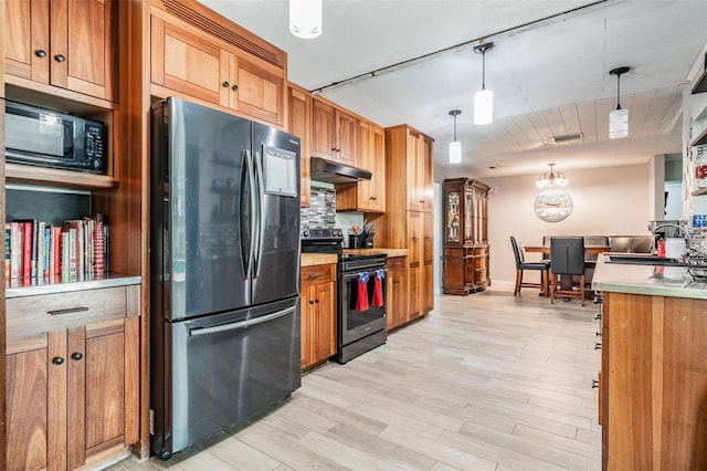 1403 Tallahassee Dr, Tarpon Springs, FL 34689 - kitchen with freestanding refrigerator, range with electric stovetop, under cabinet range hood, black microwave, and backsplash