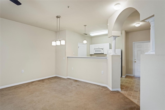 1640 Villa Capri Cir Unit 206, Odessa, FL 33556 - kitchen featuring white microwave, carpet, decorative columns, hanging light fixtures, and white cabinets