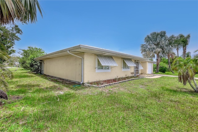 1340 NE Mariposa Dr NE, Palm Bay, FL 32905 - view of home's exterior with stucco siding, a garage, and a lawn