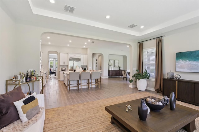 2903 Cordoba Ranch Blvd, Lutz, FL 33559 - living area featuring arched walkways, recessed lighting, a tray ceiling, and light wood-style flooring