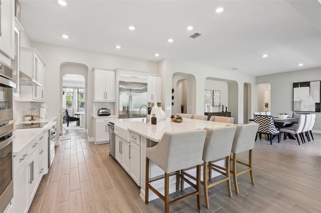 2903 Cordoba Ranch Blvd, Lutz, FL 33559 - kitchen with arched walkways, a breakfast bar area, stainless steel appliances, white cabinetry, and recessed lighting