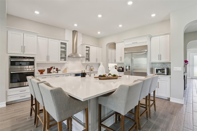 2903 Cordoba Ranch Blvd, Lutz, FL 33559 - kitchen with wall chimney exhaust hood, stainless steel appliances, arched walkways, backsplash, and a large island with sink